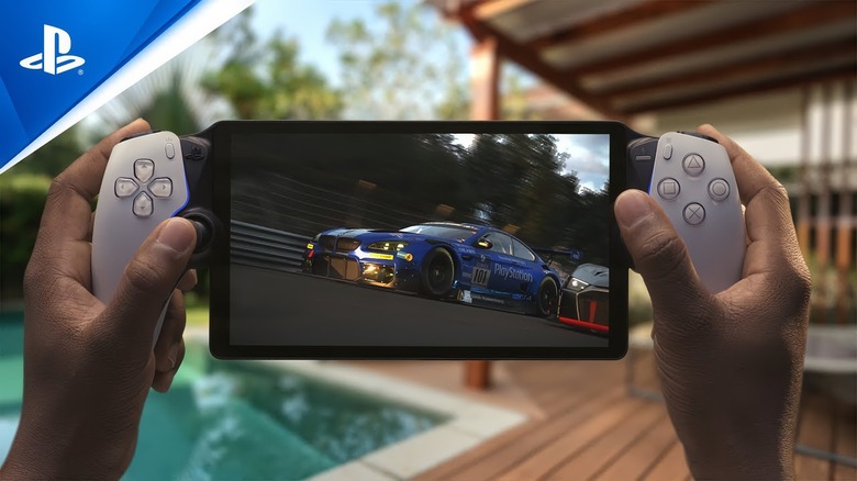 Marketing photo of the Sony PlayStation Portal remote play handheld. A person’s hands grip the portable console with a racing sim on the screen. In the background is a luxurious pool and deck with lawn chairs.