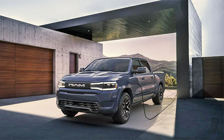A photo of the production-ready Ram 1500 REV parked in front of a modern minimal house made of concrete.