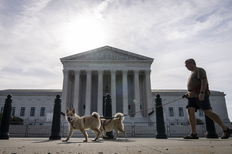 WASHINGTON, DC - JUNE 1: A man walks his dogs past the U.S. Supreme Court on June 1, 2021 in Washington, DC. The Supreme Court is set to issue several rulings this month, including cases concerning the Affordable Care Act, a dispute involving LGBT and religious rights, and a case related to voting restrictions in Arizona. (Photo by Drew Angerer/Getty Images)