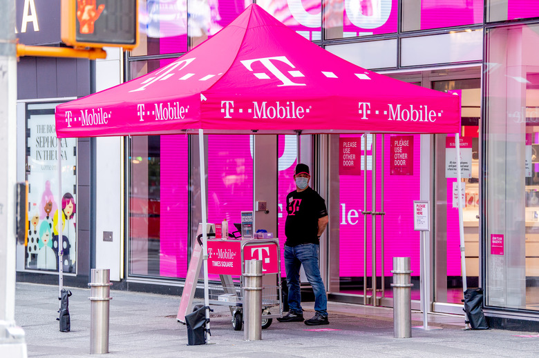 NEW YORK, NEW YORK - AUGUST 18: A clerk at the T-Mobile store in Times Square provides curb side service during the fourth phase of the coronavirus reopening on August 18, 2020 in New York, New York. The fourth phase allows outdoor arts and entertainment, sporting events without fans and media production. (Photo by Roy Rochlin/Getty Images)