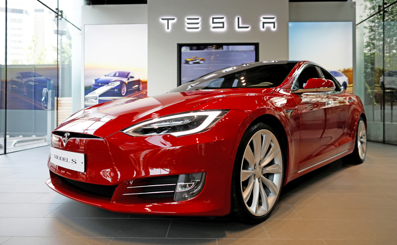 A red Tesla shown inside a Tesla showroom.
