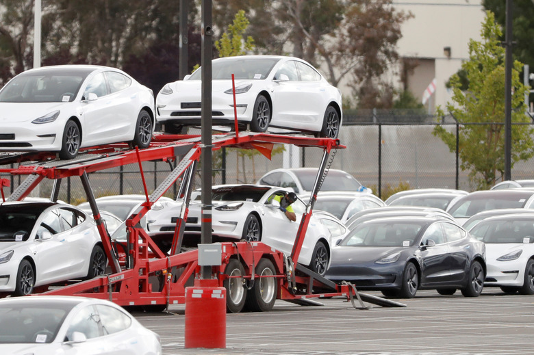 A worker loads a Tesla electric vehicle onto a car carrier trailer at Tesla's primary vehicle factory after CEO Elon Musk announced he was defying local officials' coronavirus disease (COVID-19) restrictions by reopening the plant in Fremont, California, U.S. May 11, 2020. REUTERS/Stephen Lam