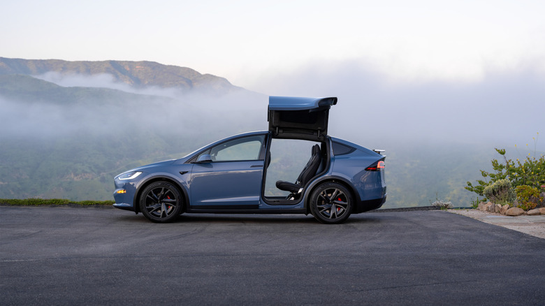 A blue sedan with a foggy mountain in the background.