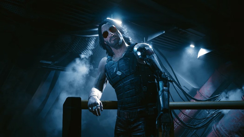 Screenshot of Keanu Reeves as Johnny Silverhand in Cyberpunk 2077. He leans against a rail.