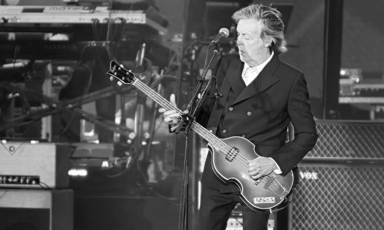 Black & white photo of Paul McCartney playing bass onstage.