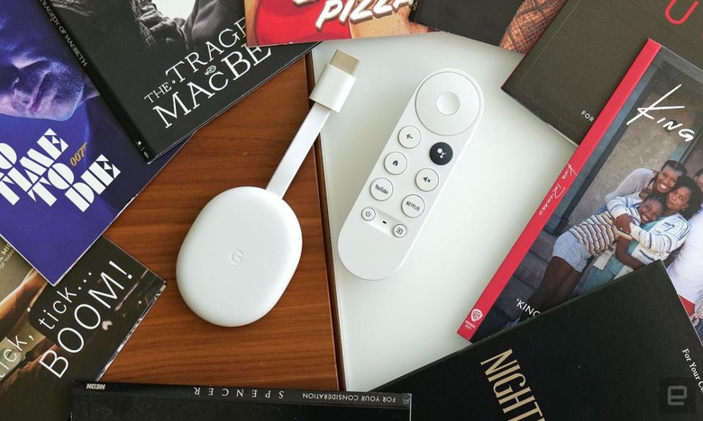 Review photo of the Chromecast with Google TV (HD). The streaming dongle and remote sit on a desk, surrounded by books.