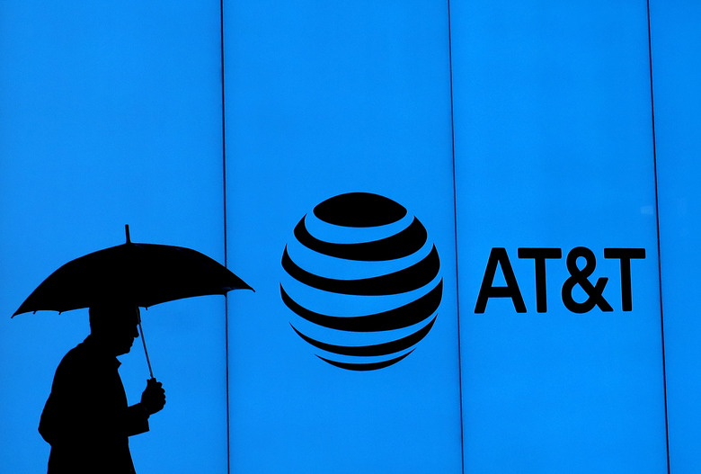 DALLAS, TEXAS - MARCH 13:  A man walks with an umbrella outside of AT&T corporate headquarters on March 13, 2020 in Dallas, Texas.  AT&T is allowing employees to work remotely from home if they have the ability to do so, as a safety measure due to COVID-19. (Photo by Ronald Martinez/Getty Images)