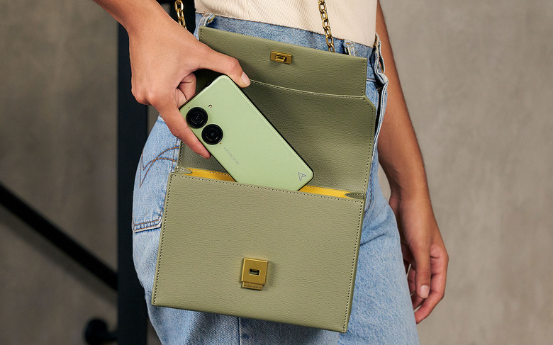 A green ASUS Zenfone 10 being inserted into a handbang.