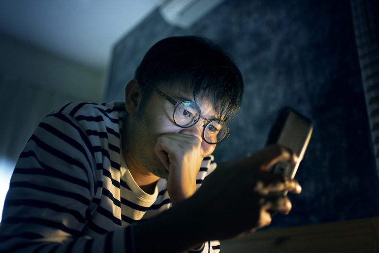 Asian man Young adult feeling worried and concerned after use smartphone on the bed