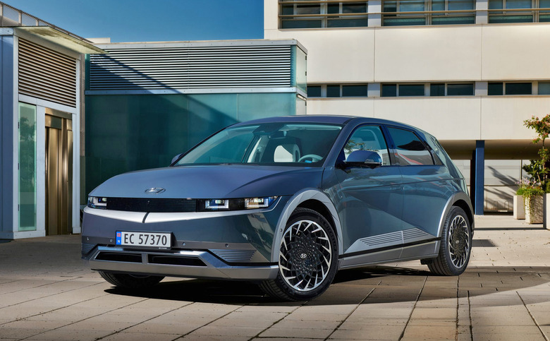 The Hyundai Ioniq 5 in blue sits parked in front of a modern building plaza.