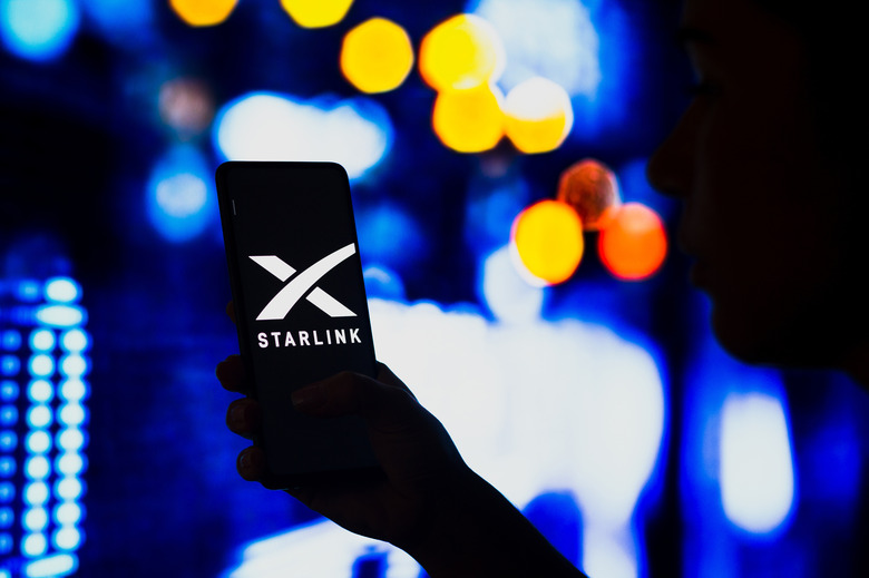 BRAZIL - 2022/05/02: In this photo illustration, a silhouetted woman holds a smartphone with the Starlink logo displayed on the screen. (Photo Illustration by Rafael Henrique/SOPA Images/LightRocket via Getty Images)