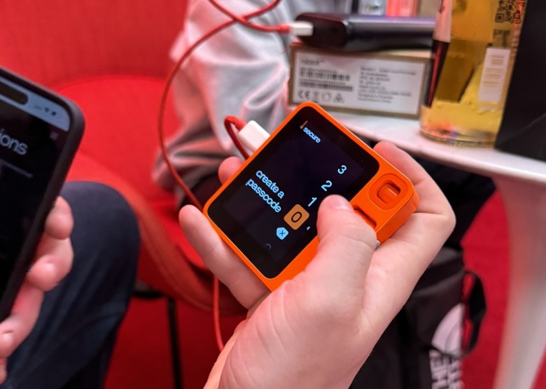 The Rabbit R1 AI device held in mid-air with the word 