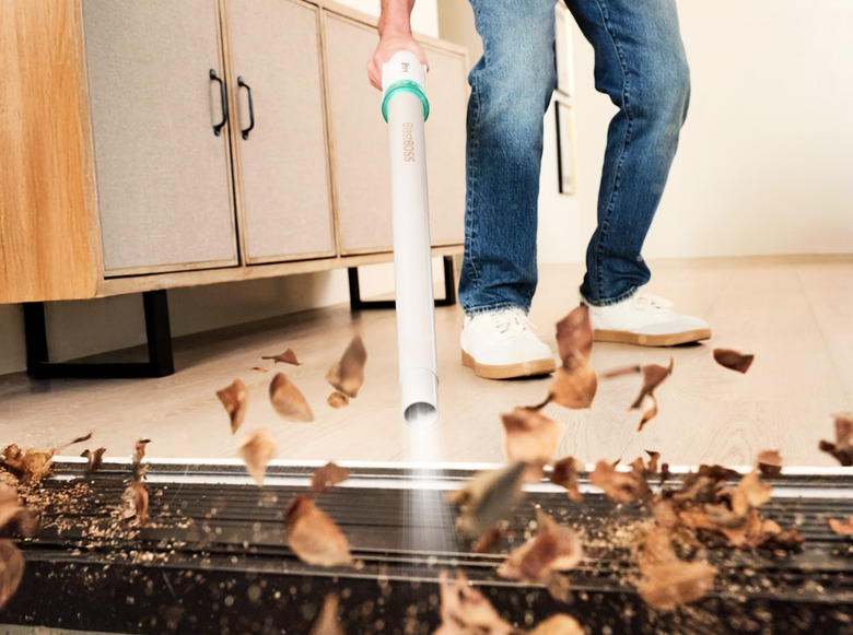 A person using the leaf blower to blow leaves.