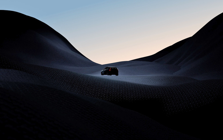 A teaser photo for the Volvo EX30 small SUV showing the silhouette of a small vehicle driving across a dark hilly terrain.