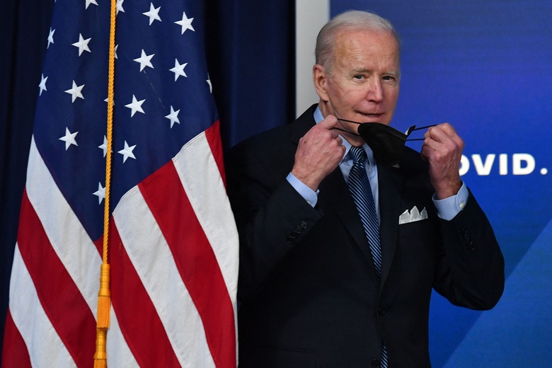 US President Joe Biden removes his protective mask while arrving to deliver remarks on Covid-19 in the South Court Auditorium, next to the White House, in Washington, DC, on March 30, 2022. (Photo by Nicholas Kamm / AFP) (Photo by NICHOLAS KAMM/AFP via Getty Images)