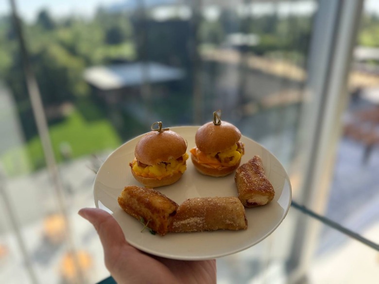 A smiley face made out of two brioche sliders and three french toast bites on a white plate held up in front of the WWDC keynote stage.