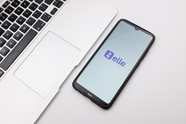 In this photo illustration a Zelle logo seen displayed on a smartphone screen on a desk next to a Macbook in Athens, Greece on September 29, 2022. (Photo Illustration by Nikolas Kokovlis/NurPhoto via Getty Images)
