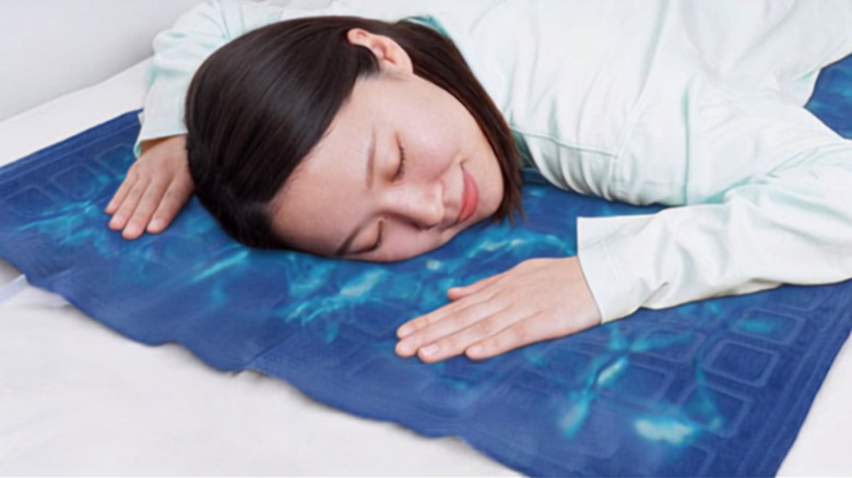 A woman laying on the Flowing Water Mat Lite with her eyes closed, smiling.