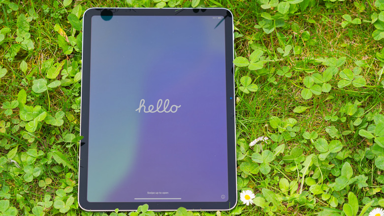 iPad Air sitting on the grass outside, showing "Hello" screen