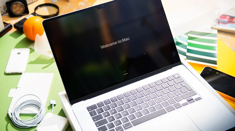 MacBook Air on a desk displaying "Welcome to Mac" text on-screen