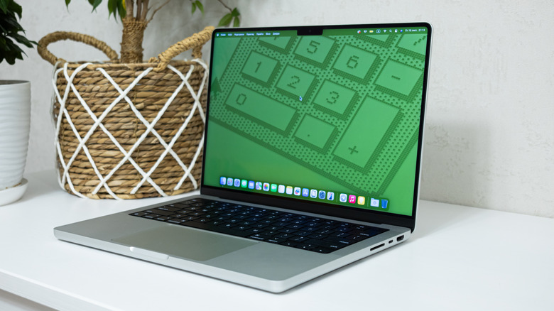 MacBook Pro on a desk, showing a green retro calculator wallpaper