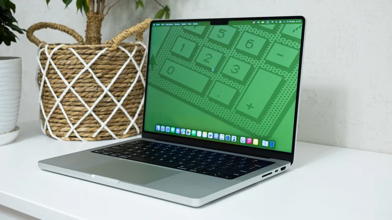 MacBook Pro on a desk, showing a green retro calculator wallpaper