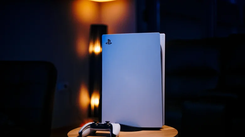 A PS5 in a vertical position in a darkened room.