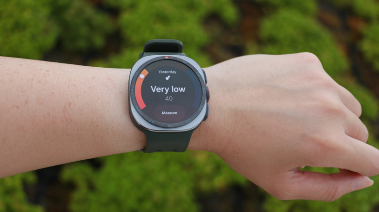 The Galaxy Watch Ultra 2 on a person's wrist raised up in front of a field, its screen showing antioxidant test results saying "Very low."