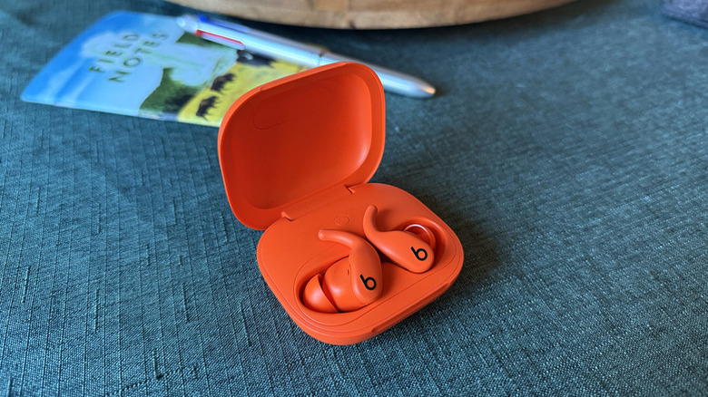 Powerbeats Fit earbuds sitting in their charging case.