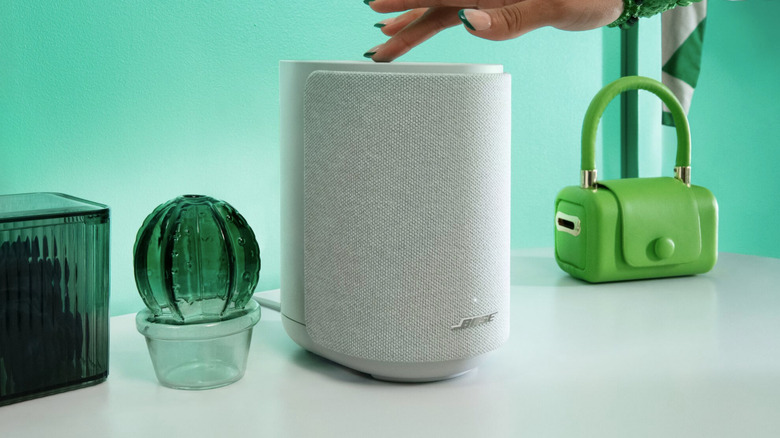 A hand operates a Bose speaker.