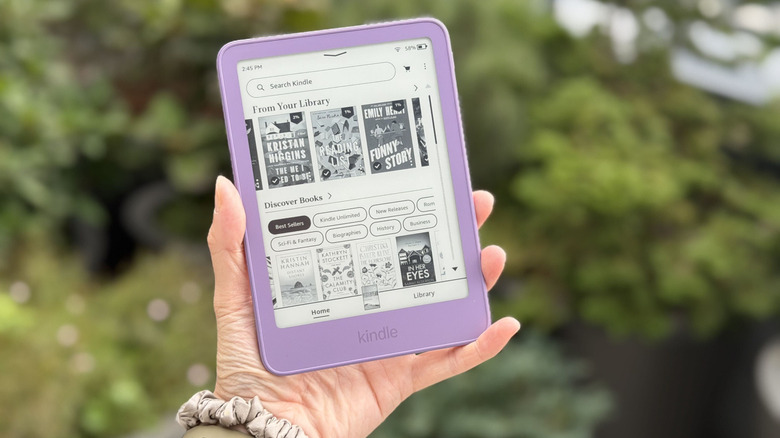 A hand holding a purple e-reader.
