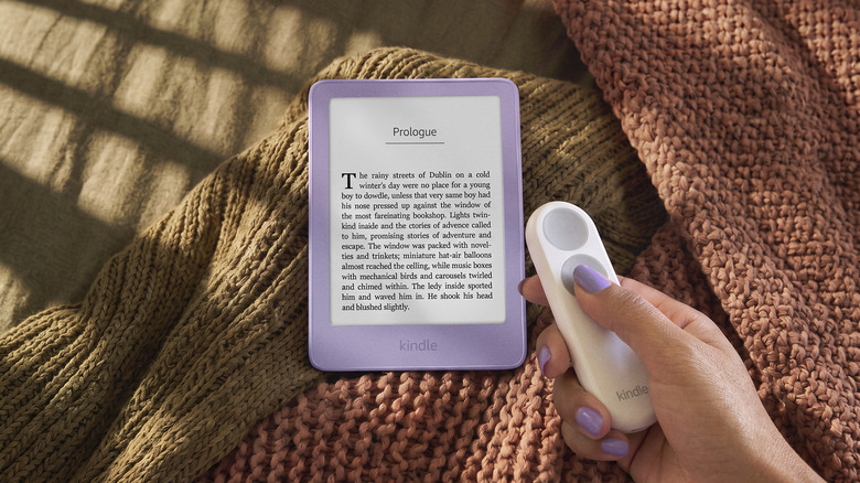 A hand holding the Kindle Click in front of a purple Kindle.