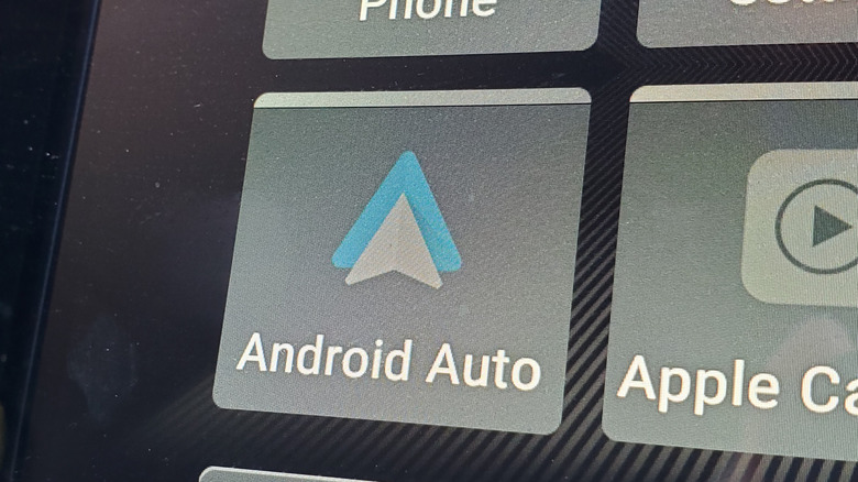 An enlarged car screen with the Android Auto  and Apple CarPlay app icons visible