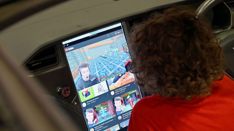 A person watches a YouTube video on a car display.