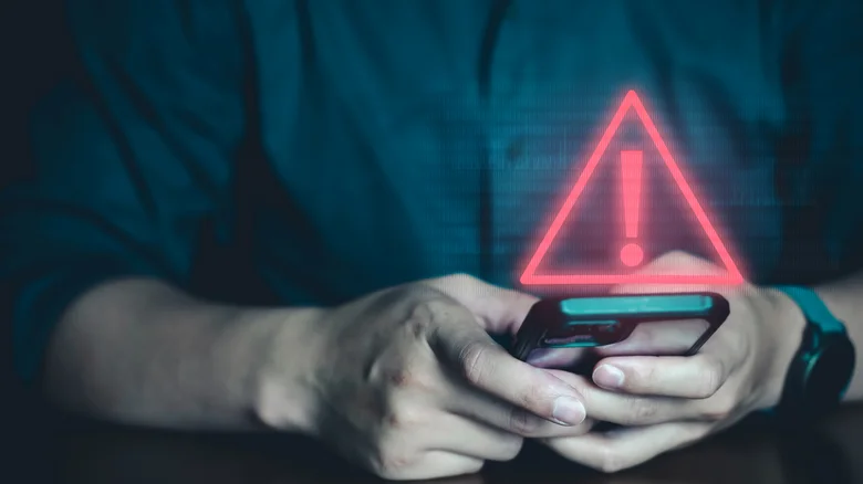 Person using smartphone with a red warning sign overlaid above it.