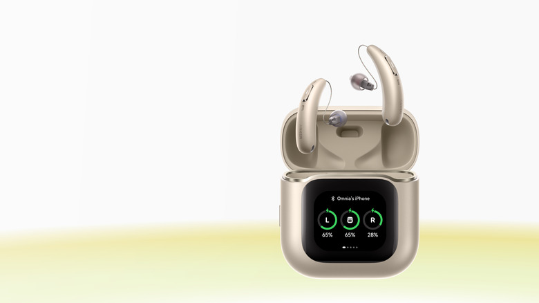 Photo of an Anker RIC Hearing Aid. The aids are rendered above the case, all in a pale bronze finish. The case shows a black screen with battery information.
