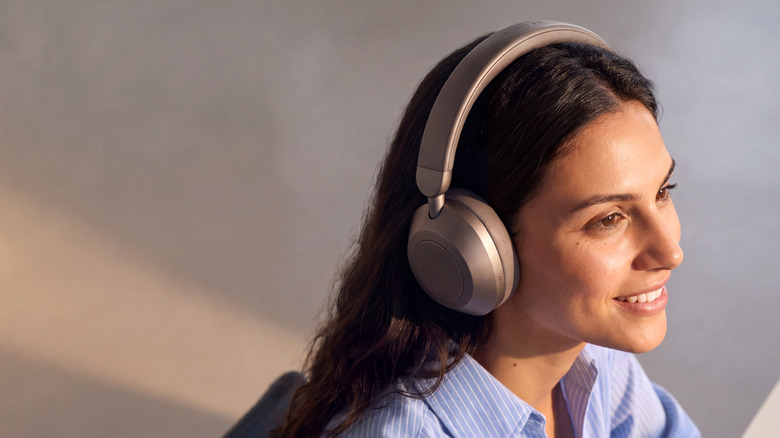 Photo of a brunette woman wearing Anker Space 2 Pro headphones in a metallic taupe finish.