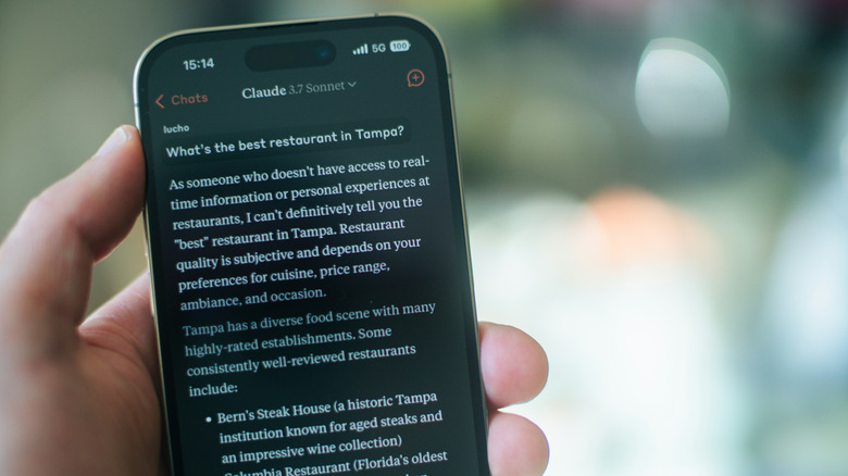 Closeup of a phone, in hand, showing the Claude AI chatbot