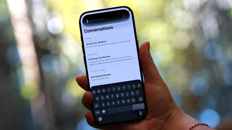 An iPhone 18 Pro held up in mid-air showing the Siri app and Siri in the dynamic island.
