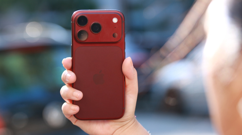 A burgundy iPhone 18 Pro held up in mid air.