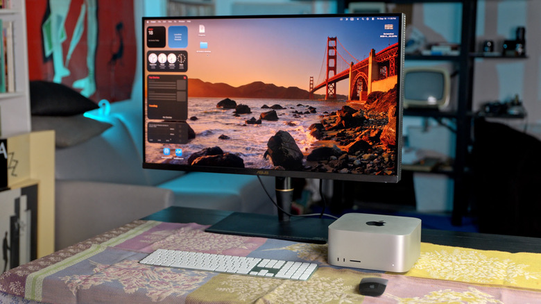 The Mac Studio M5 Ultra is shown with a monitor in an office setup with a dark background