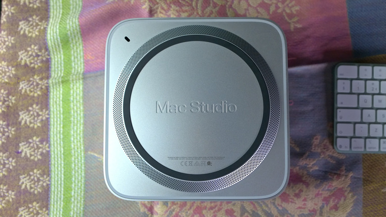 The Mac Studio M5 Ultra computer is shown from the bottom with the speaker and base