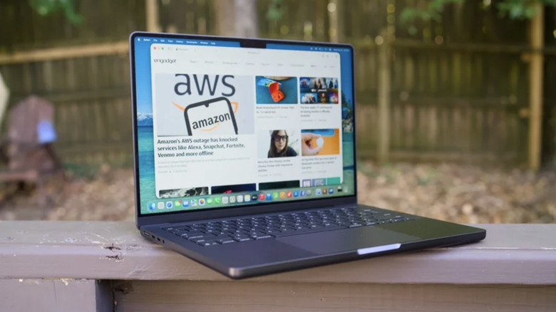 Photo of a MacBook Pro displaying the Engadget website. The laptop is placed on top of a wooden railing in a backyard with wooden fencing in the background.
