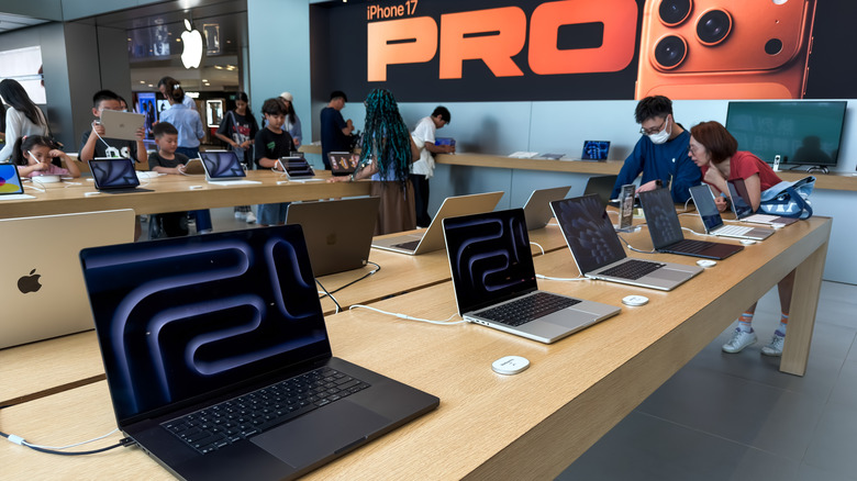 A row of MacBooks is shown in an Apple Store.