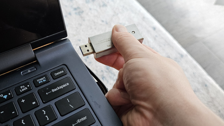 Close-up of a hand inserting a Kingston flash drive into a laptop.