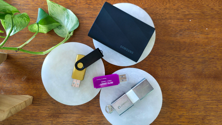 An assortment of USB flash drives and an SSD on a table.