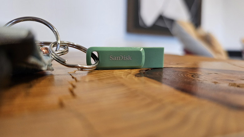 A teal SanDisk flash drive on a keychain.