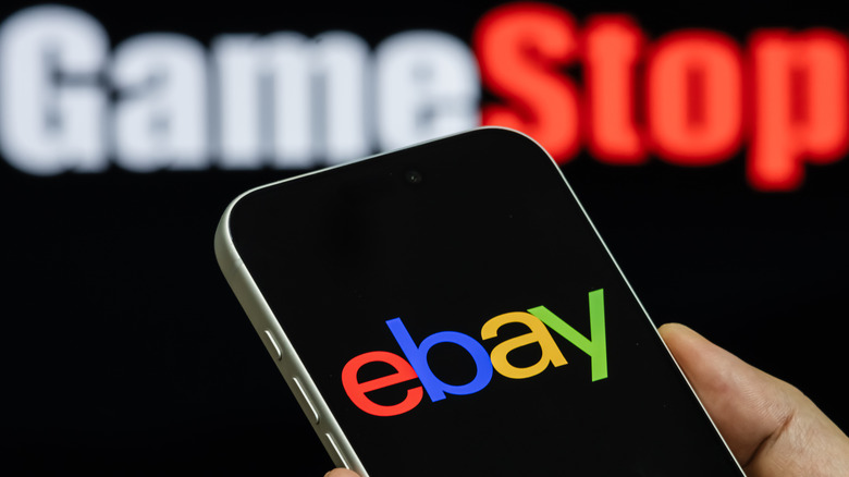 A phone with the eBay logo on it, with the GameStop logo behind