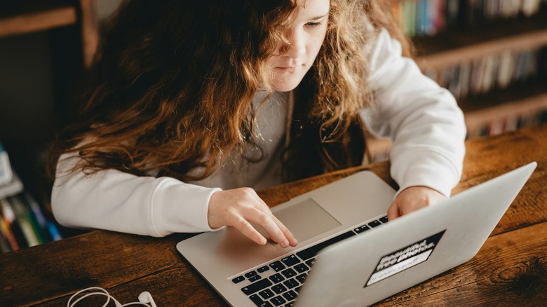 A child concentrates while using a laptop.