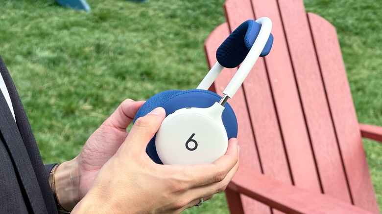White Beats 360 with blue ear cushions being held in hands.